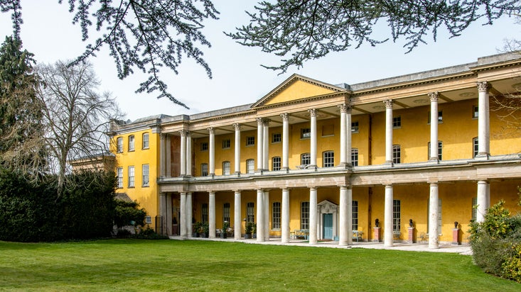 A long, bright yellow Portico with over 2 dozen classical columns across the ground floor and first storey of the house.